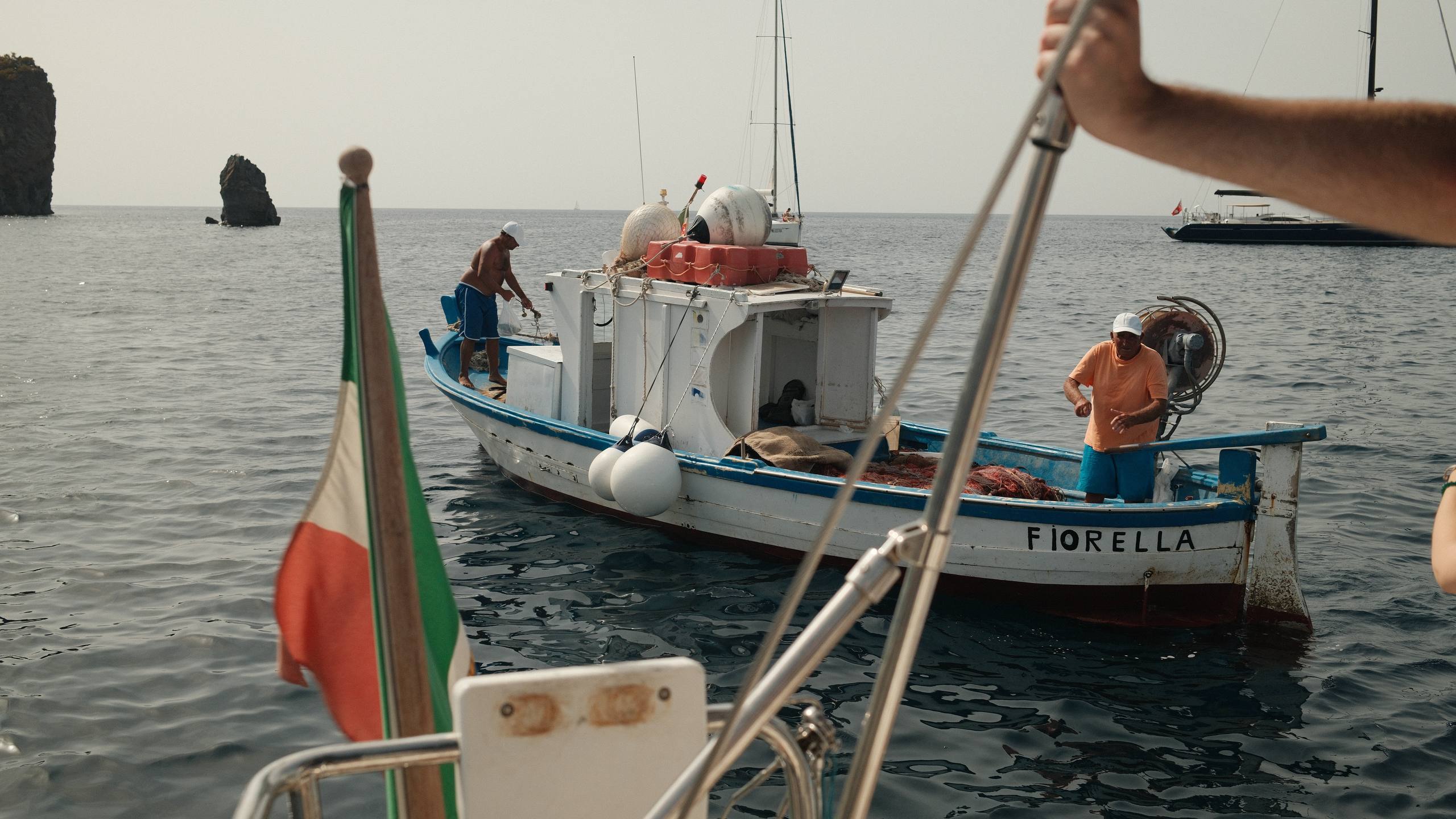 Italian fisherman in a small boat by yacht